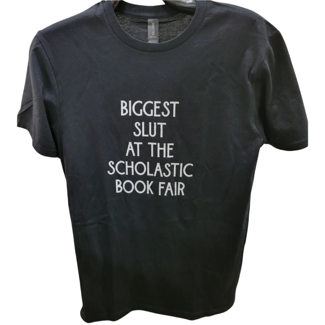 Black t-shirt with white text 'BIGGEST SLUT AT THE SCHOLASTIC BOOK FAIR' on a white background